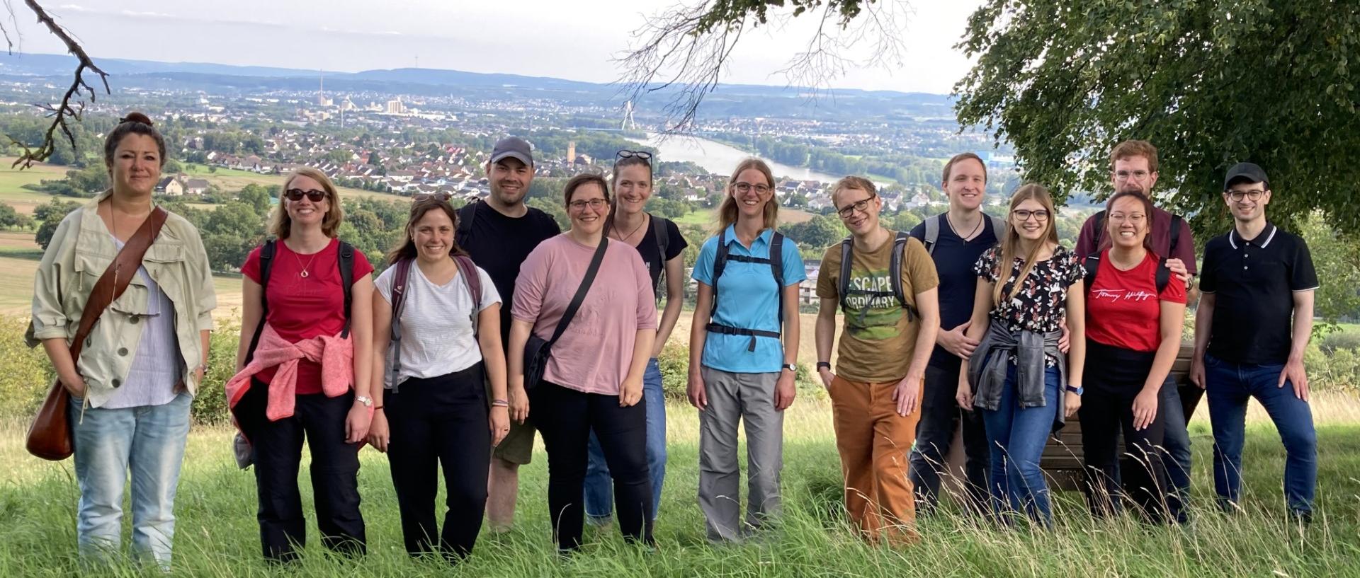 Mehrere Menschen schauen zufrieden in eine Kamera. Sie stehen auf einem Aussichtspunkt mit Blick ins Neuwieder Becken