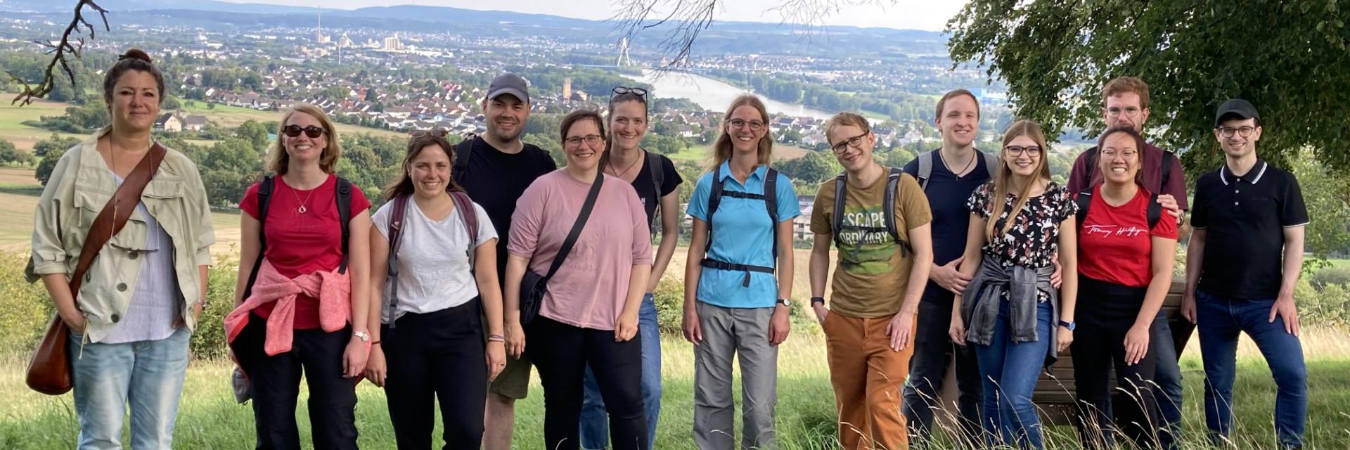 Mehrere Menschen schauen zufrieden in eine Kamera. Sie stehen auf einem Aussichtspunkt mit Blick ins Neuwieder Becken